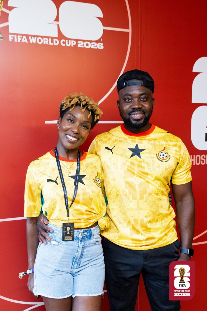 Sally-Ann and Nathan in front of a FIFA 2026 World Cup promotion board